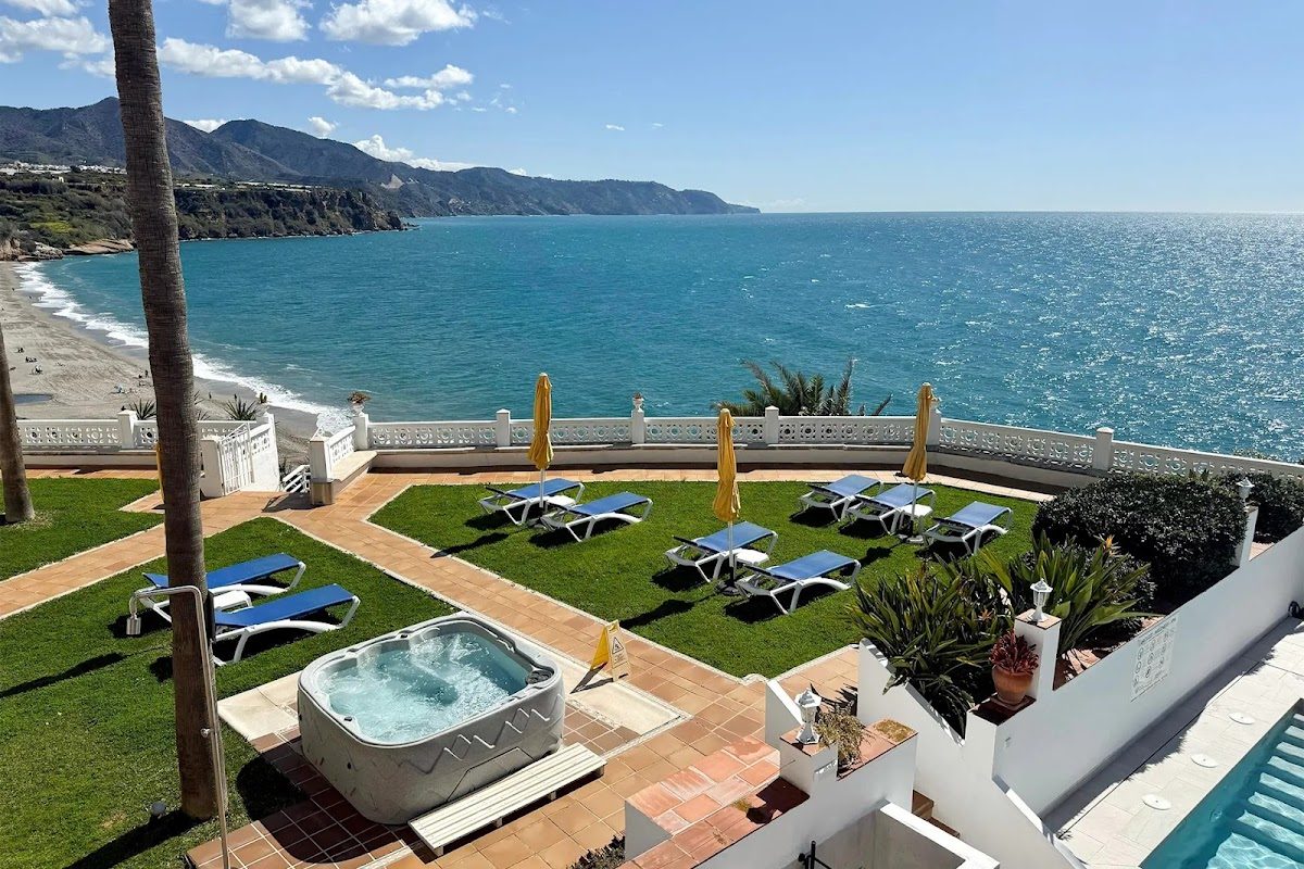 Hotel Paraíso del Mar features a pool area with sun loungers and a view of the beach and mountains.