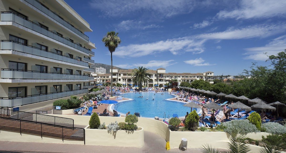 Hotel Puente Real features a large outdoor pool surrounded by sun loungers and palm trees.