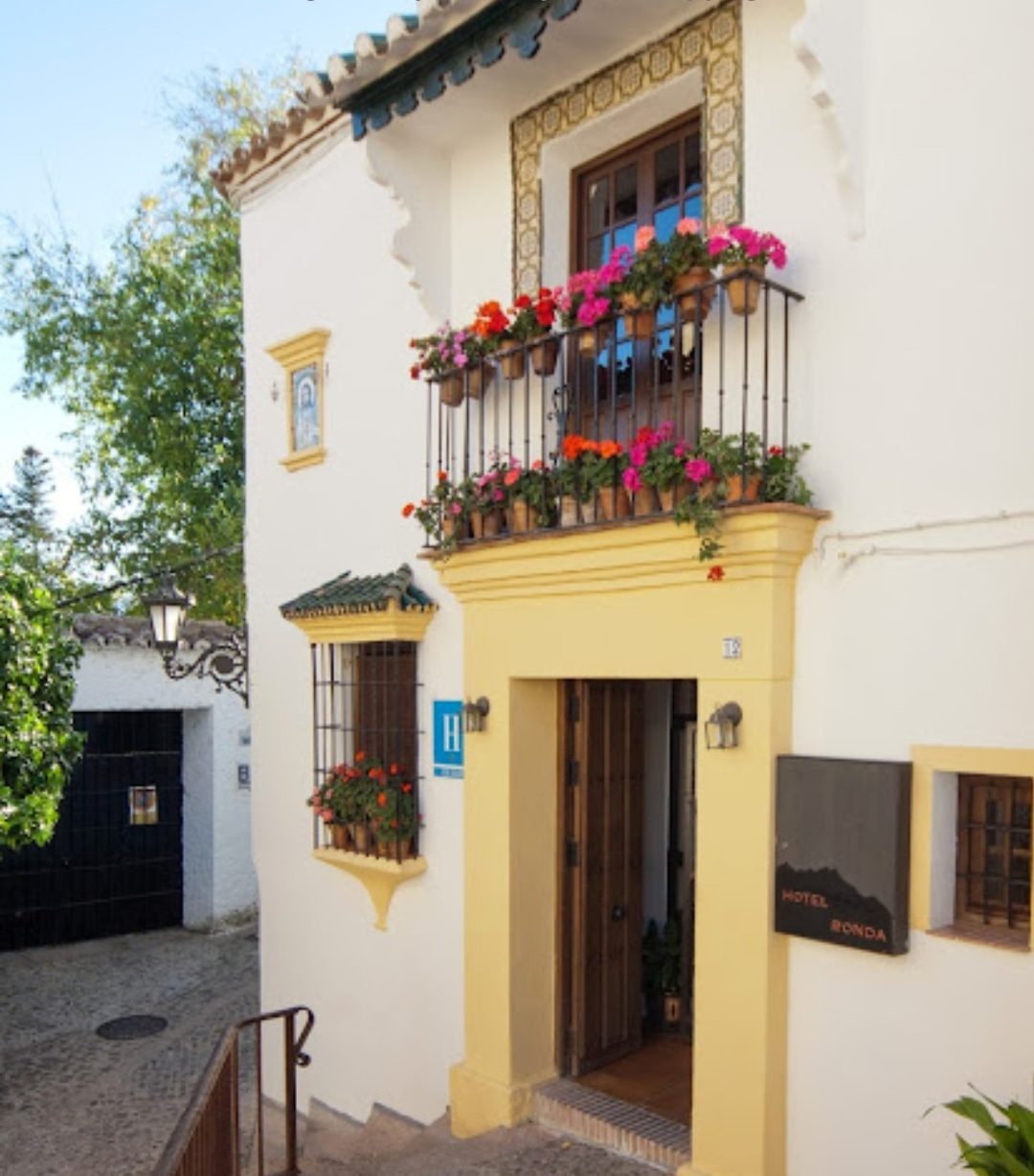 El Hotel Ronda presenta una encantadora fachada con coloridas flores y una entrada acogedora.