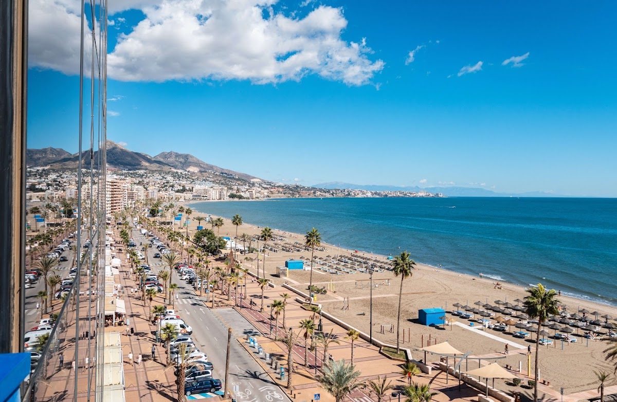 View of the beach and coastline from Hotel Yaramar, with palm trees and clear blue skies.