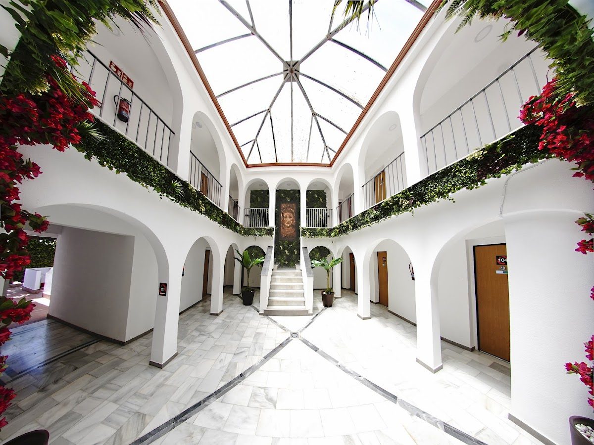 The interior of Hotel Zen Airport features a bright atrium with plants, marble flooring, and a central staircase.