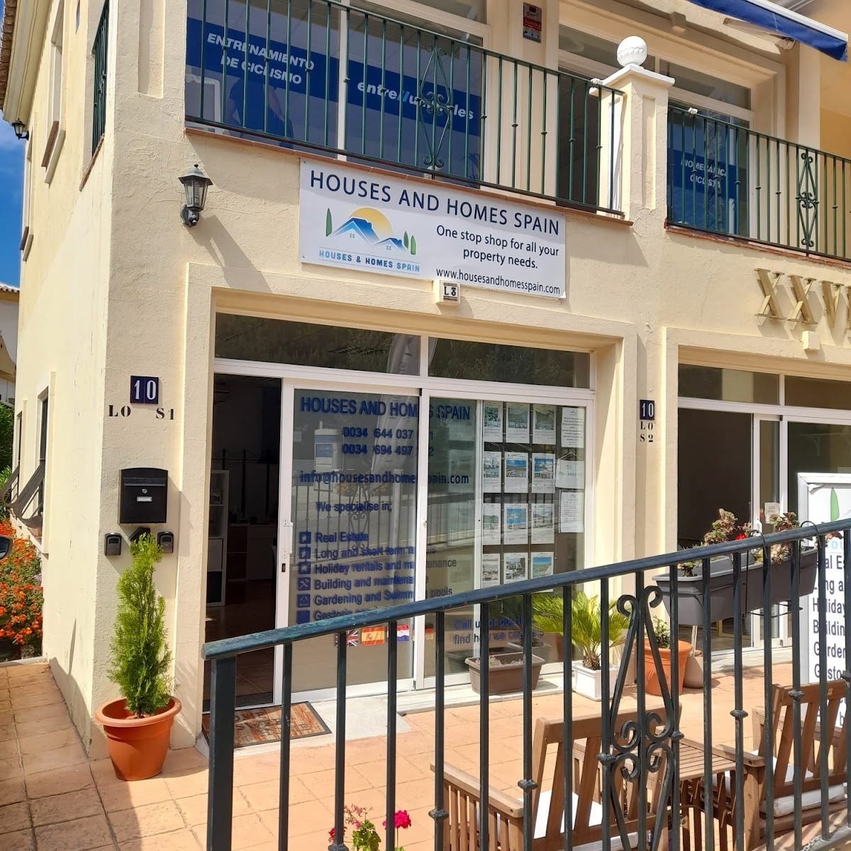 El exterior de Casas y Viviendas España cuenta con una entrada acogedora con señalización y una exposición de listados de propiedades.