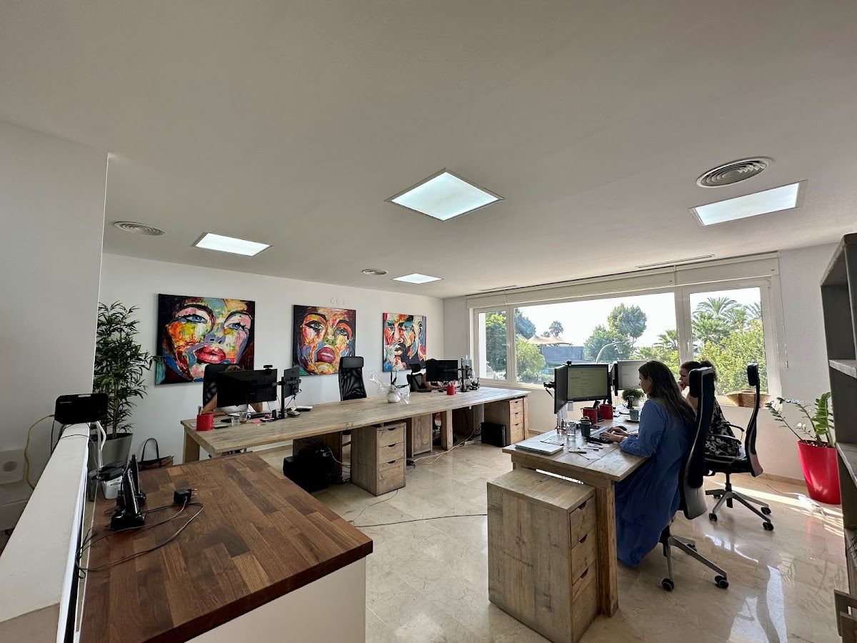 Modern office space at Hypotienda Insurance Agency with colorful artwork and a view of greenery outside.