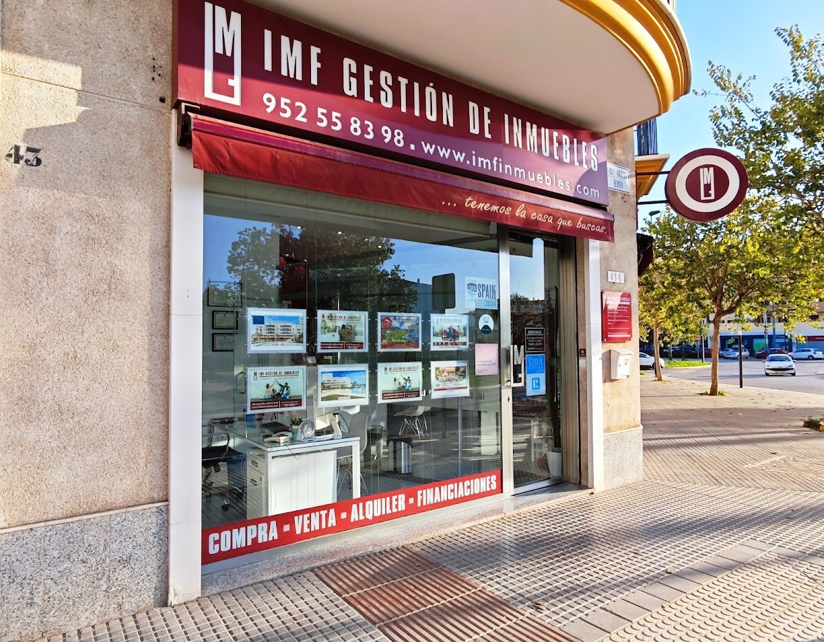 IMF GESTIÓN DE INMUEBLES storefront with property listings displayed in the windows on a sunny day.