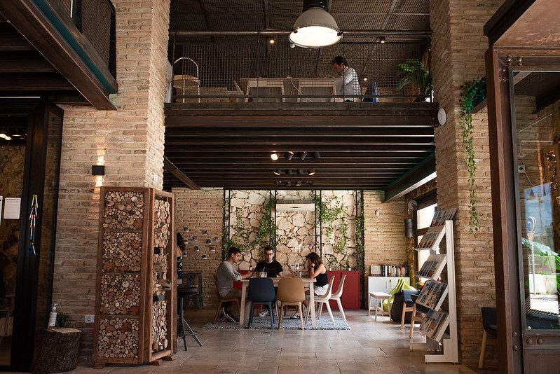 Impact Hub Málaga cuenta con un interior amplio y moderno con detalles en madera y un espacio de trabajo colaborativo.