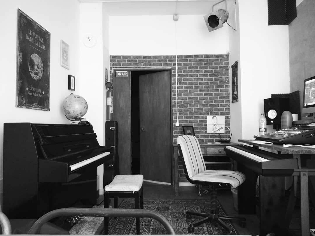 Interior de Indiana Estudio con pianos, un escritorio y una pared de ladrillos.