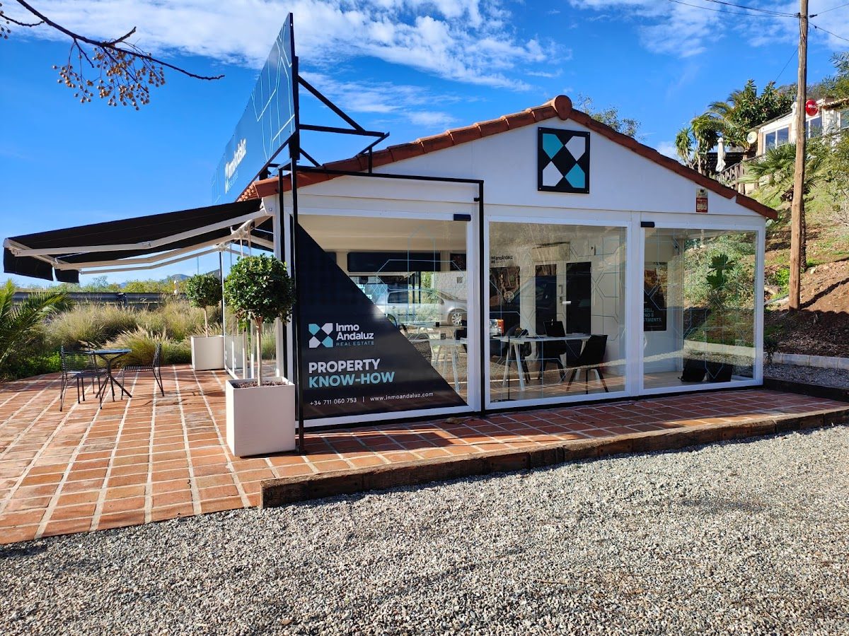 La oficina de la agencia inmobiliaria Inmo Andaluz cuenta con un diseño moderno, grandes ventanales y una acogedora zona exterior.