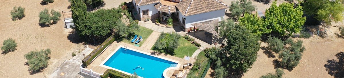 Vista aérea de una casa con piscina rodeada de árboles y terreno abierto, cerca de Inmobiliaria Ática en Ronda.