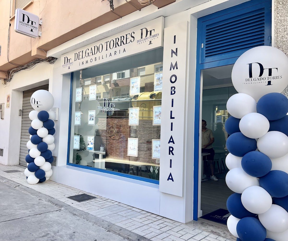 Inmobiliaria Delgado Torres features a modern storefront with blue and white balloon decorations and property listings displayed in windows.