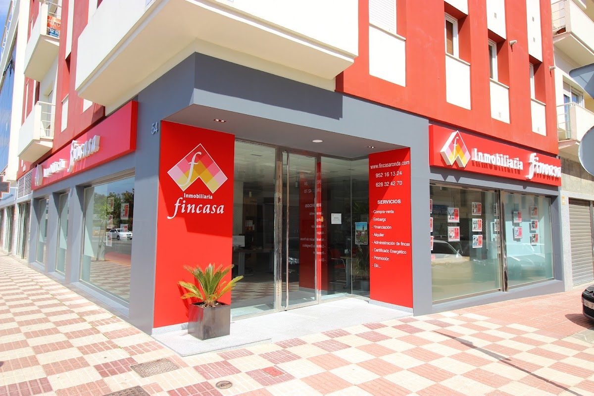 Inmobiliaria Fincasa presenta un exterior moderno con detalles en rojo y gris y grandes ventanales de cristal.