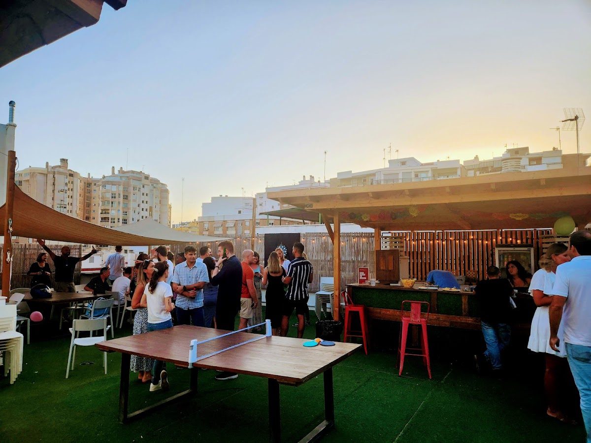 La imagen muestra una animada terraza en la azotea del Innovation Campus, con gente socializando y disfrutando de la puesta de sol.