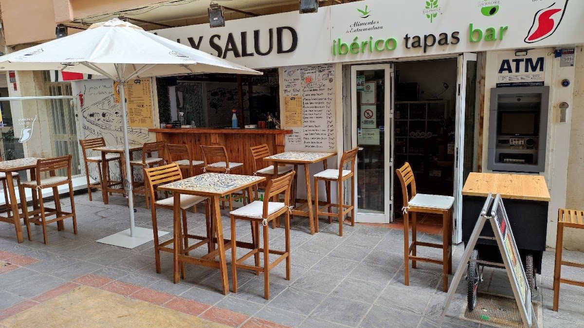 Terraza con mesas y sillas de madera en el bar de tapas Jamón y Salud Ibérico en Fuengirola.
