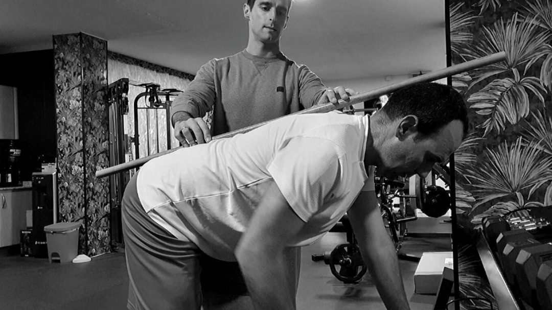 Un entrenador ayuda a un cliente con un ejercicio de fitness en JLV TRAINING en Alhaurín el Grande.