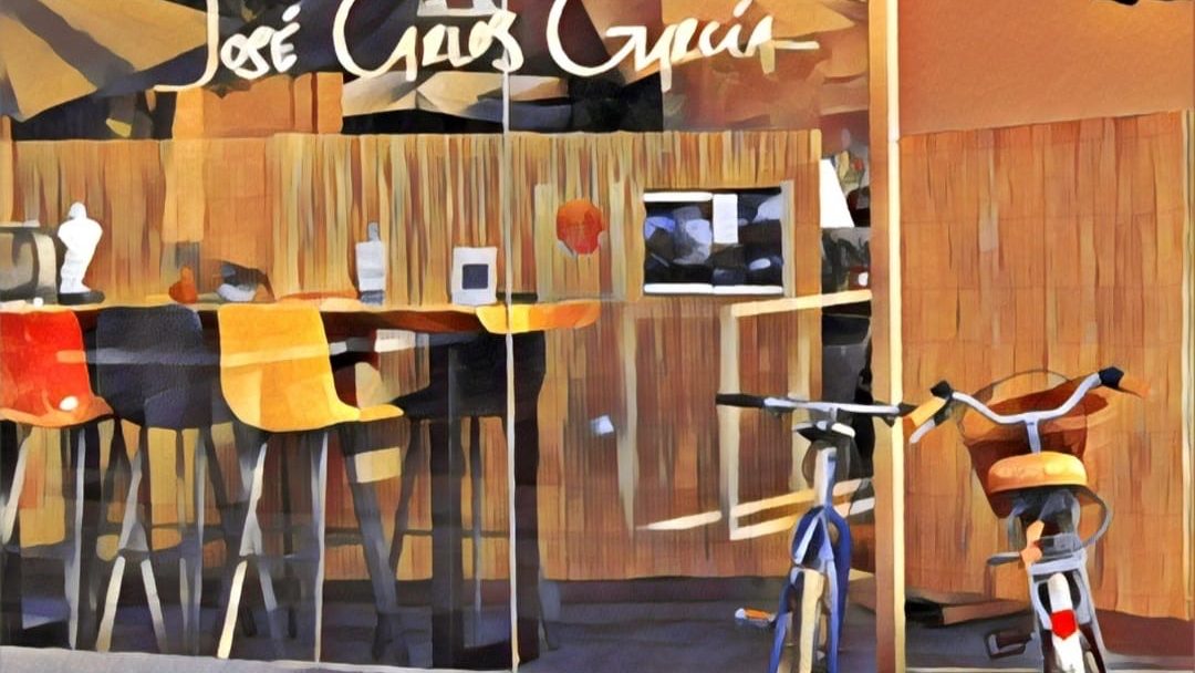 La imagen muestra el exterior del restaurante José Carlos García, con coloridos taburetes de bar y bicicletas aparcadas fuera.