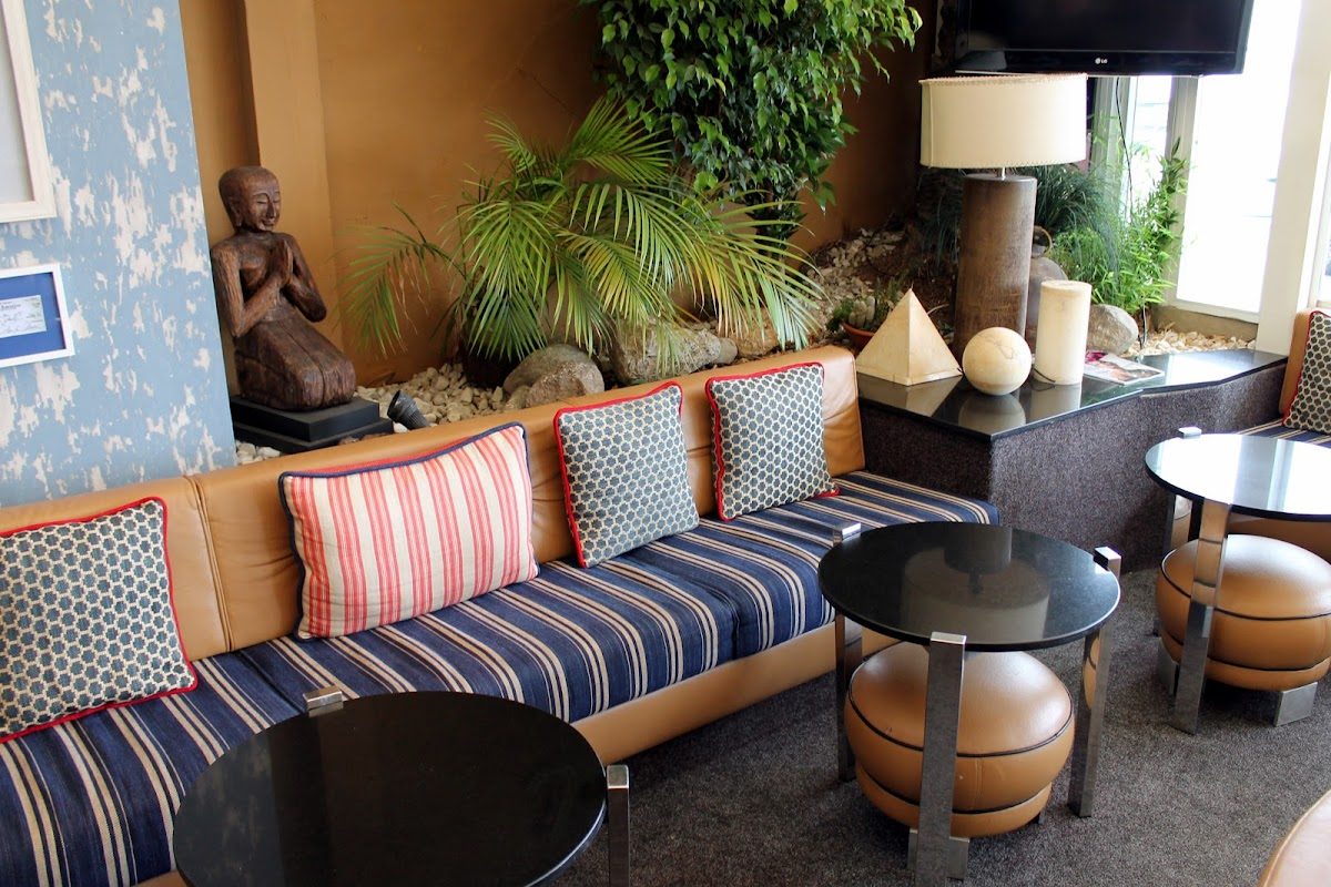 Zona de estar interior en Joys Live con cojines a rayas, mesas pequeñas y plantas decorativas.