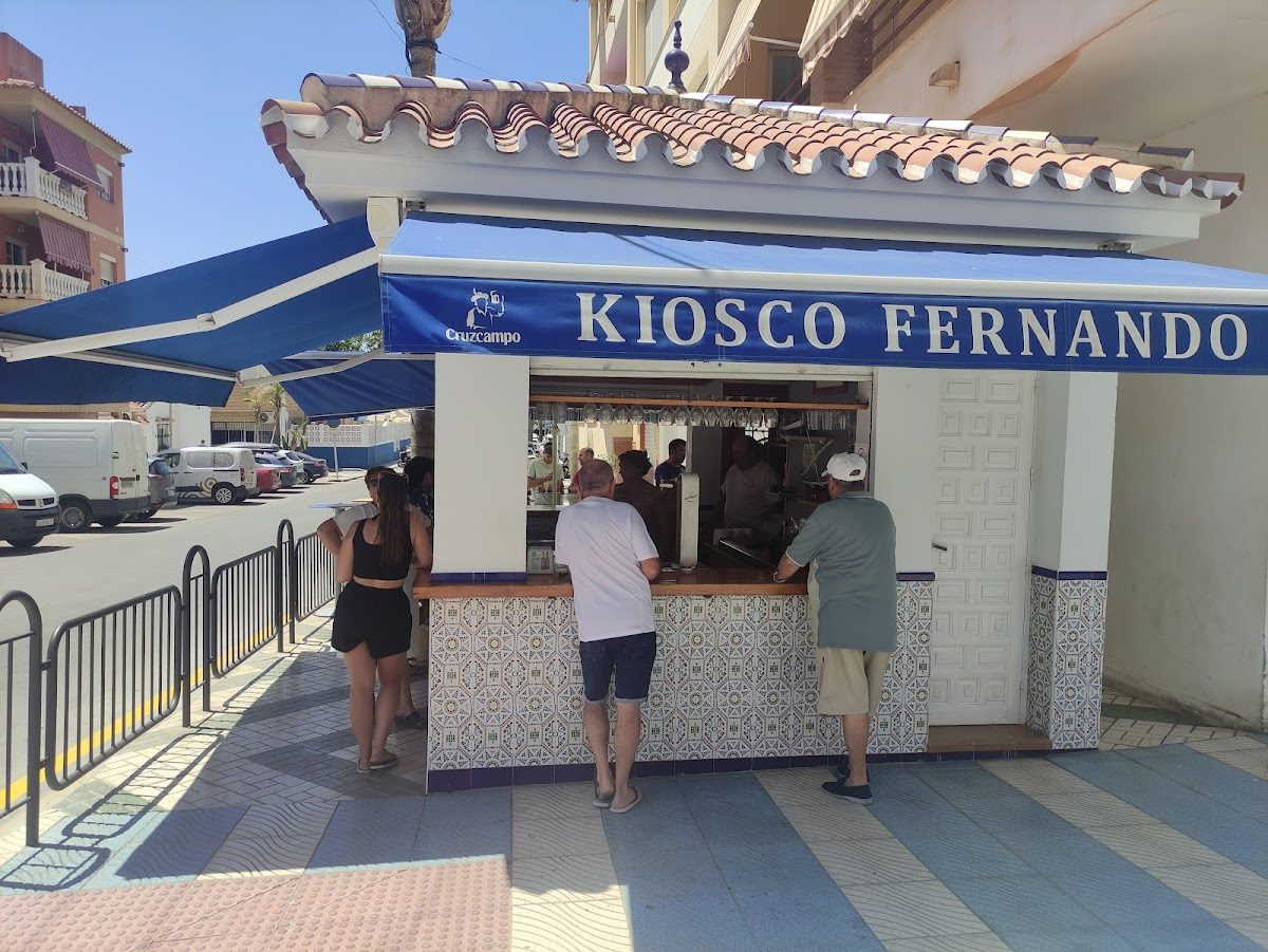 Kiosco Fernando features a small outdoor counter with patrons ordering drinks under a blue awning.