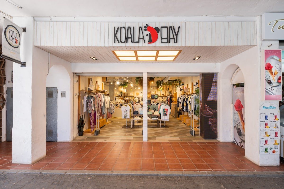 Koala Bay Benalmádena Puerto cuenta con una fachada luminosa que exhibe una variedad de ropa y accesorios.