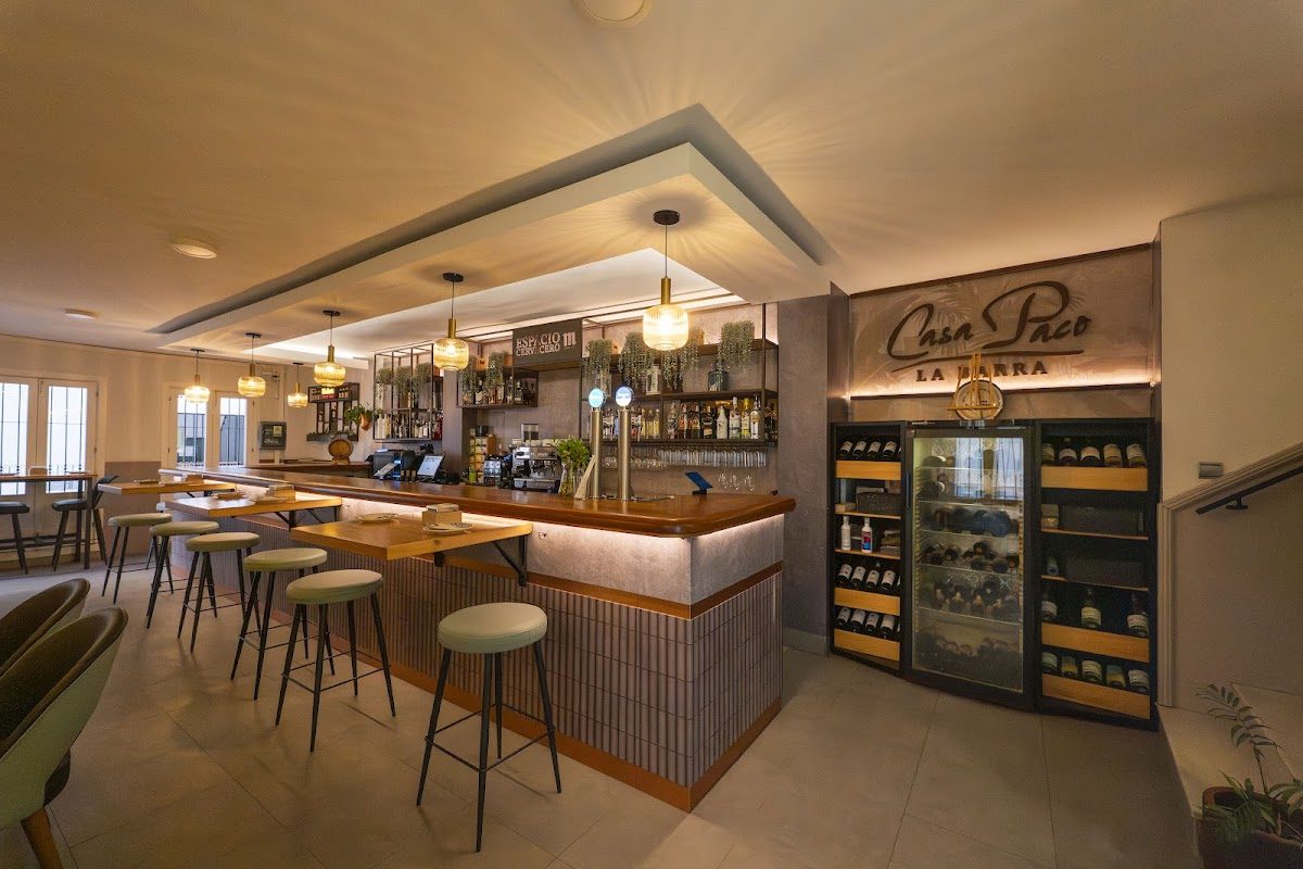 Interior view of La Barra de Casa Paco featuring a wooden bar, seating, and a wine display.