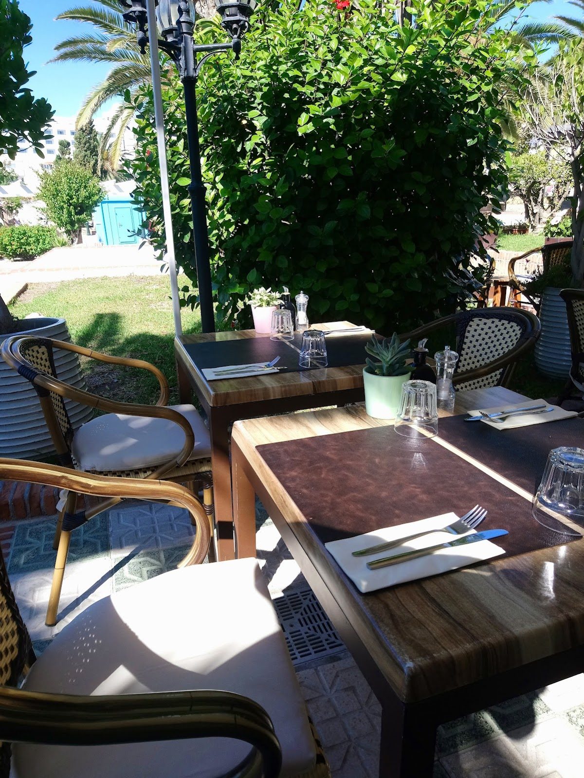 Outdoor seating with wooden tables and chairs surrounded by greenery at La Bottega Food & Wine in Nerja.
