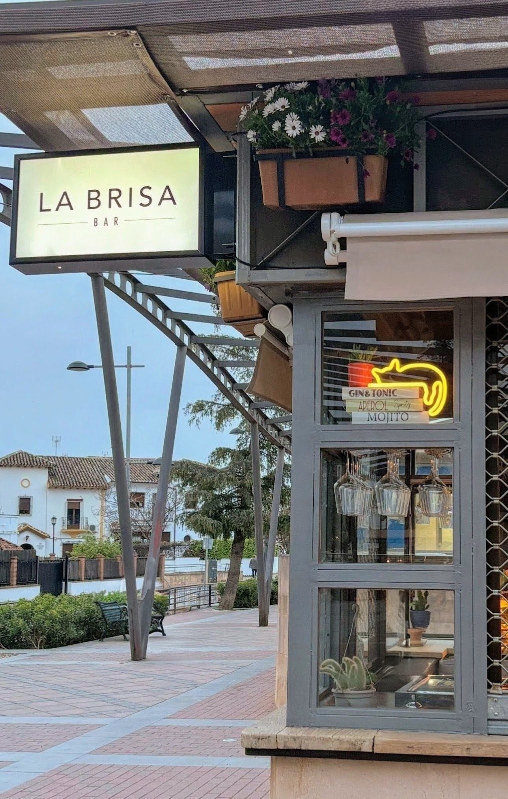 La Brisa Bar features a modern exterior with a sign and a window displaying drinks and a neon sign.