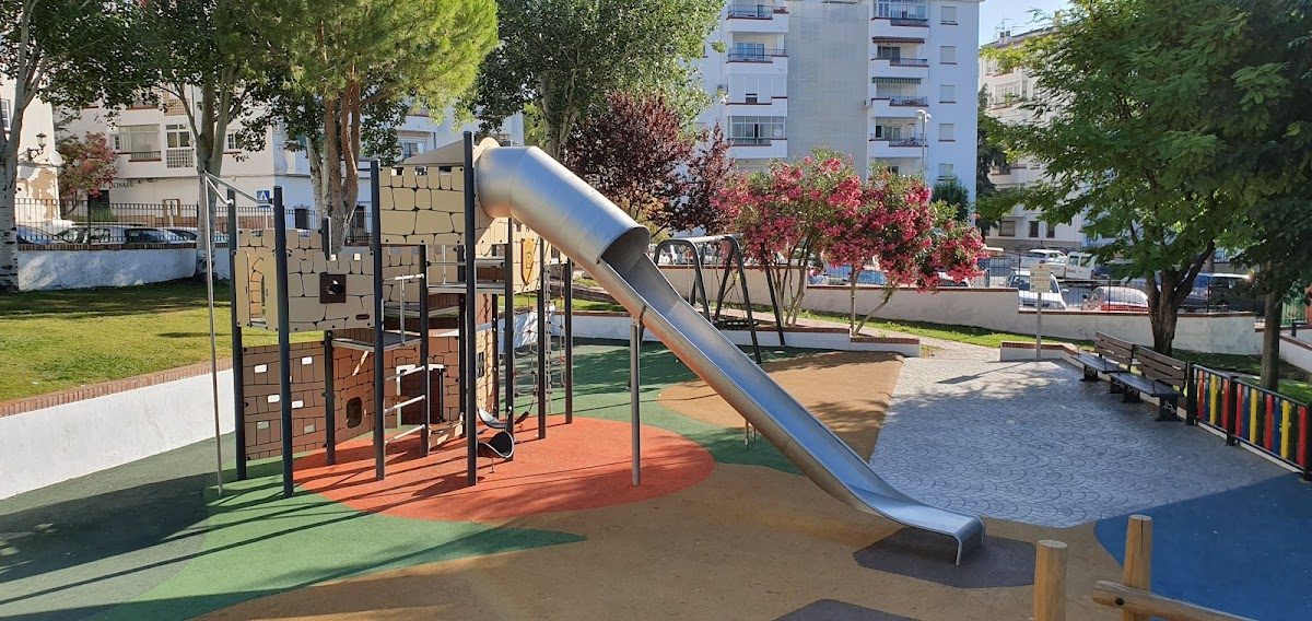A playground at La pequeña Ronda featuring a slide, climbing structure, and colorful play areas.