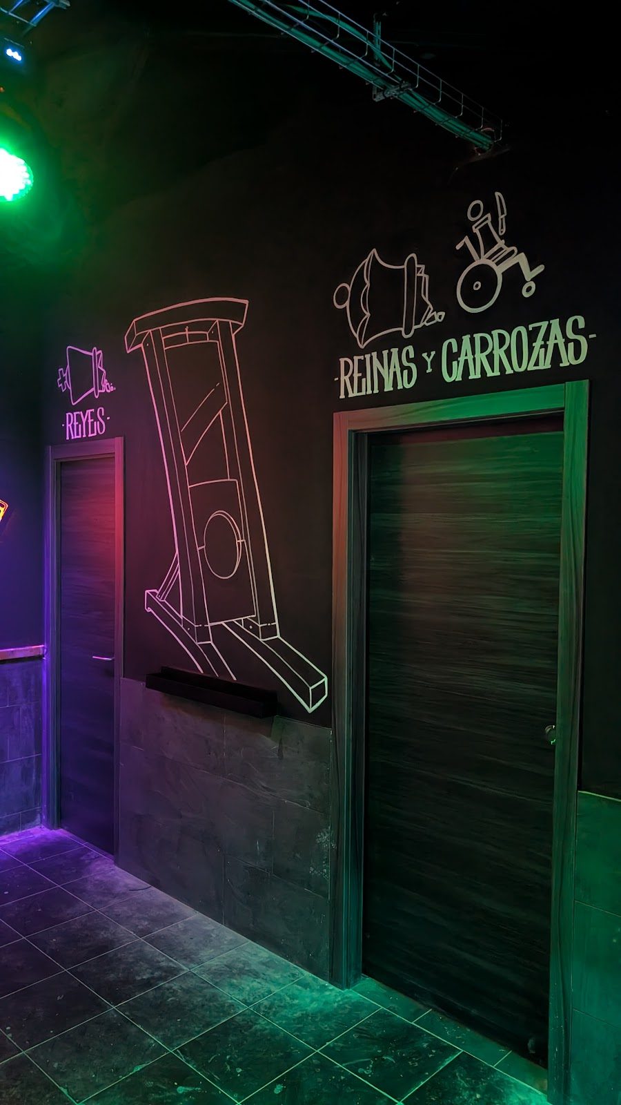 Interior del club de música La Revancha, con diseños artísticos en las puertas e iluminación colorida.