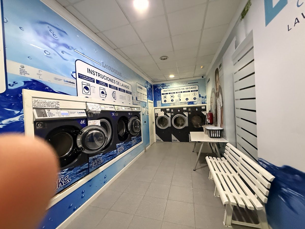 Lacolada features a bright laundry area with washing machines, drying machines, and seating for customers.