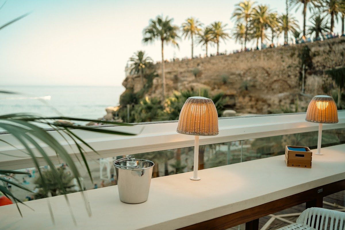 Lamalaka Nerja features a scenic terrace with palm trees, ocean views, and stylish lighting.