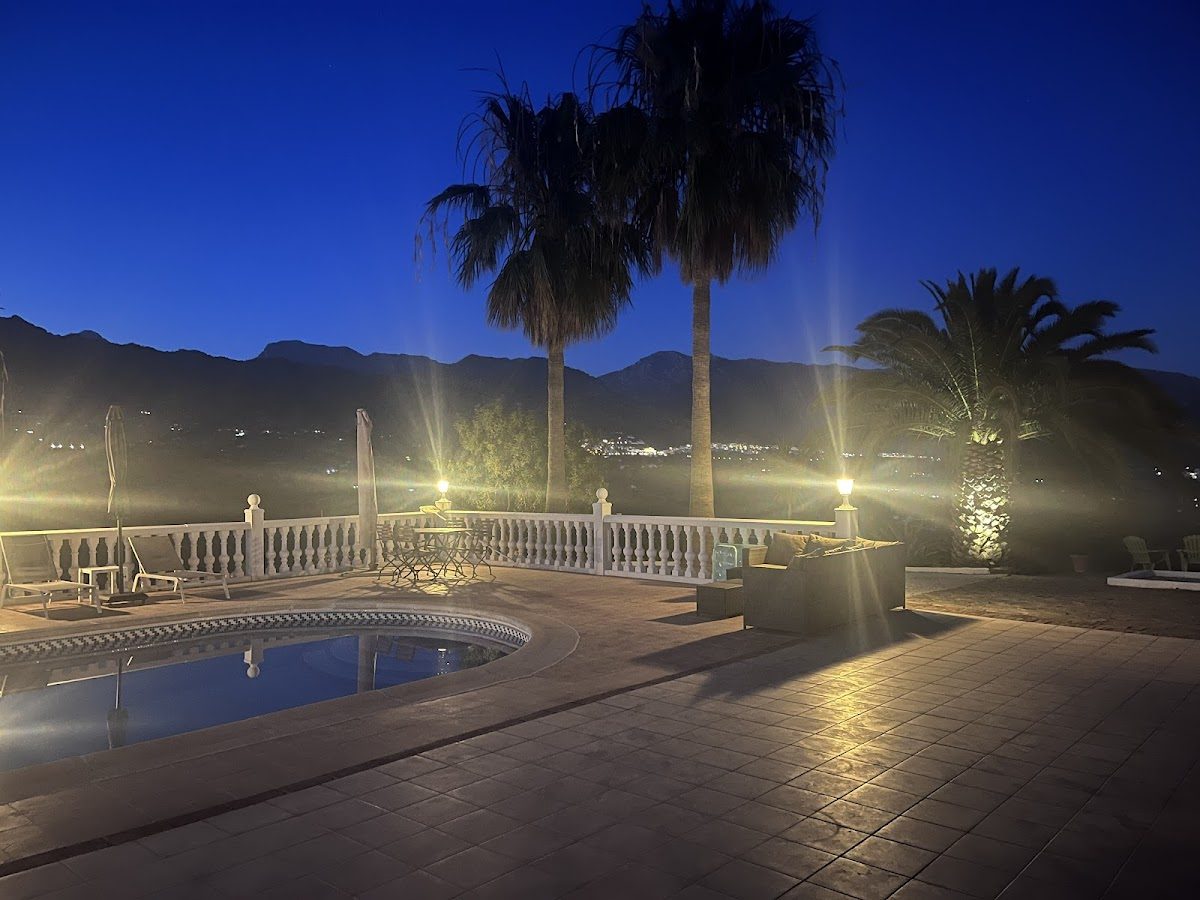 Los Barquitos cuenta con una zona de piscina con palmeras y vistas a la montaña, iluminada por la noche.