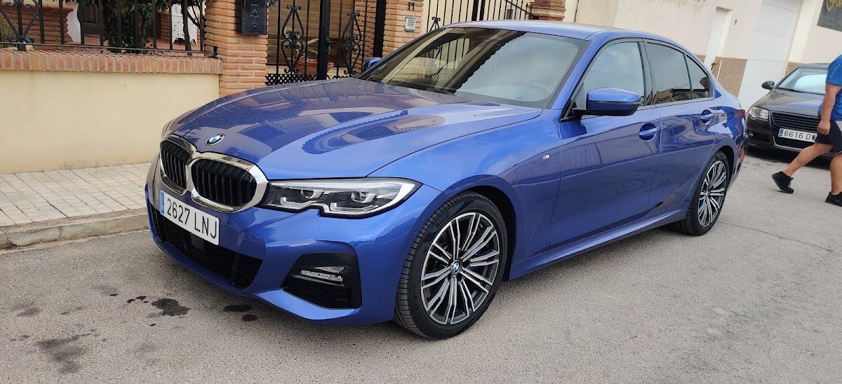 A blue BMW sedan parked on the street outside Lovers Car Care in Mollina, Málaga.