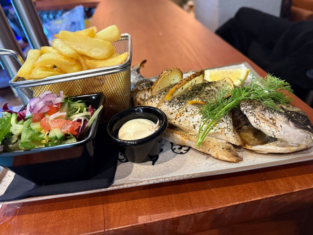 Pescado a la plancha servido con patatas fritas, ensalada y salsa en el Lunch Bar Los Amigos en Alhaurín el Grande.