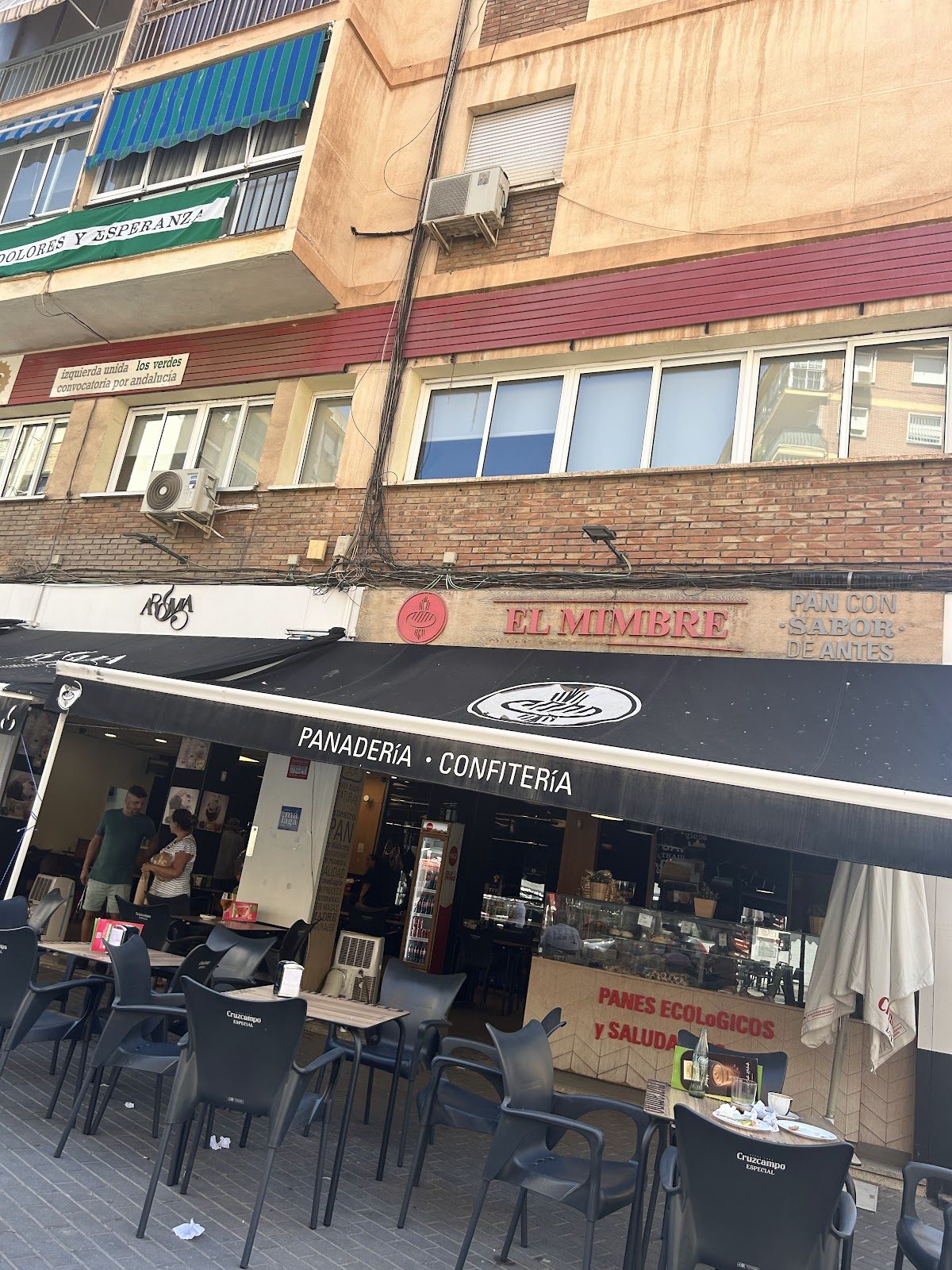 Vista exterior de la panadería El Mimere con terraza y letreros en Nueva Andalucía, Marbella.