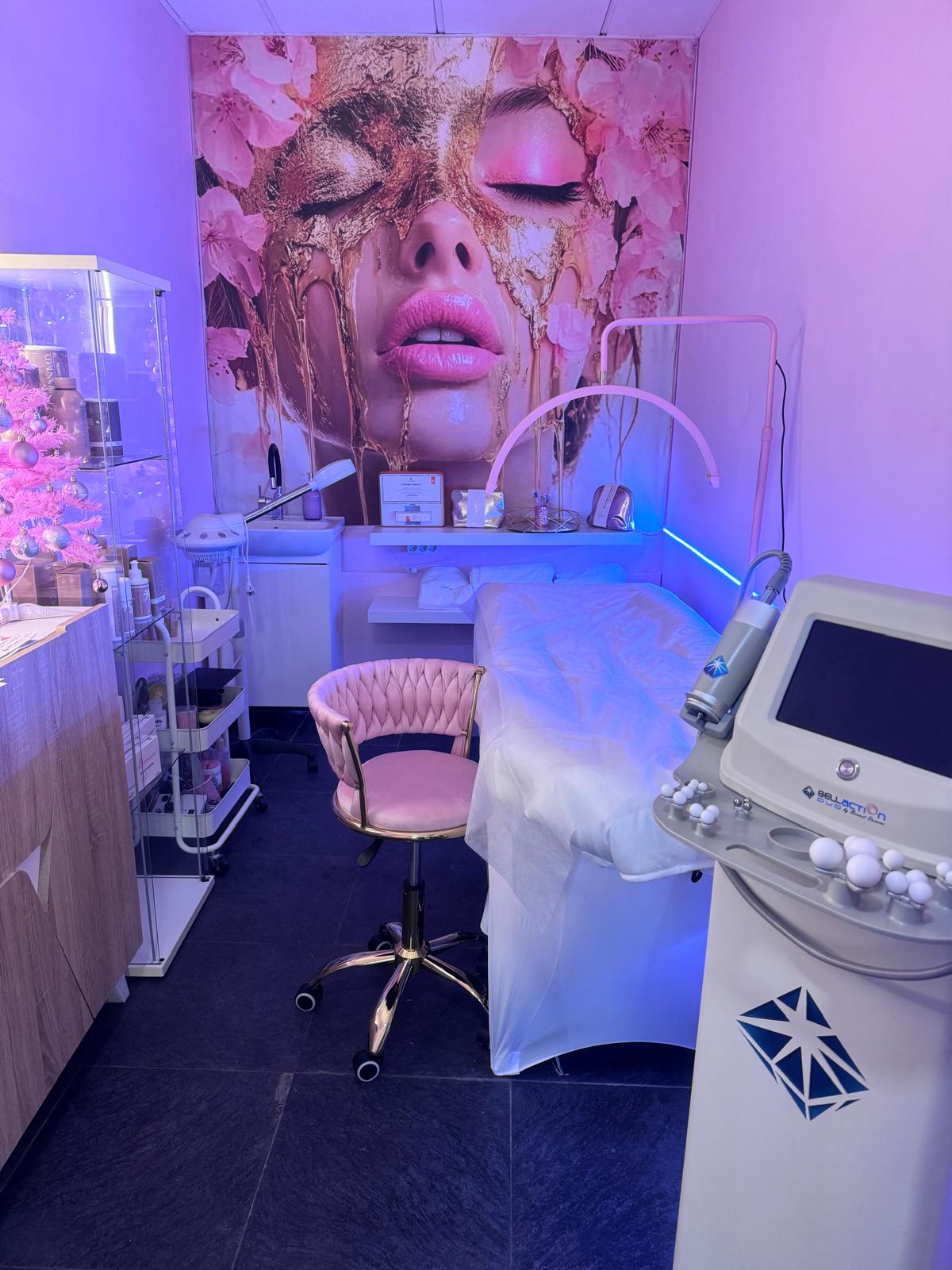 Una sala de tratamiento en Mary Estética Integral que cuenta con una estética rosa, una camilla de tratamiento y equipos de belleza.