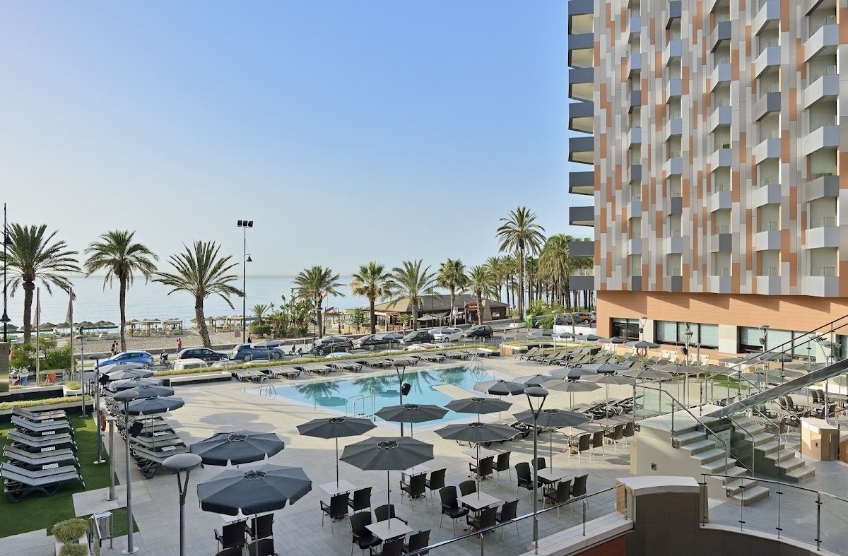 The Meliá Costa del Sol features a pool area surrounded by palm trees and sun loungers, with a beachfront view.