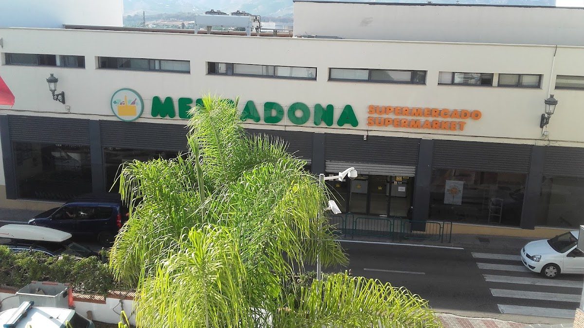 Mercadona supermarket exterior featuring green signage and palm trees in front.