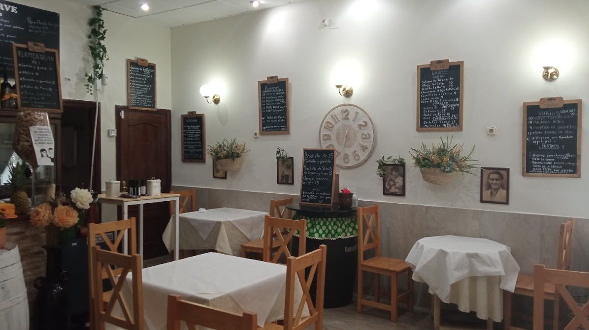 Cozy interior of Mesón Adarve featuring wooden tables, chalkboard menus, and decorative plants.