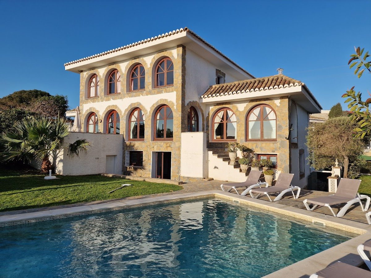 Mijas Castle features a spacious villa with a pool, surrounded by lush greenery and sunny skies.