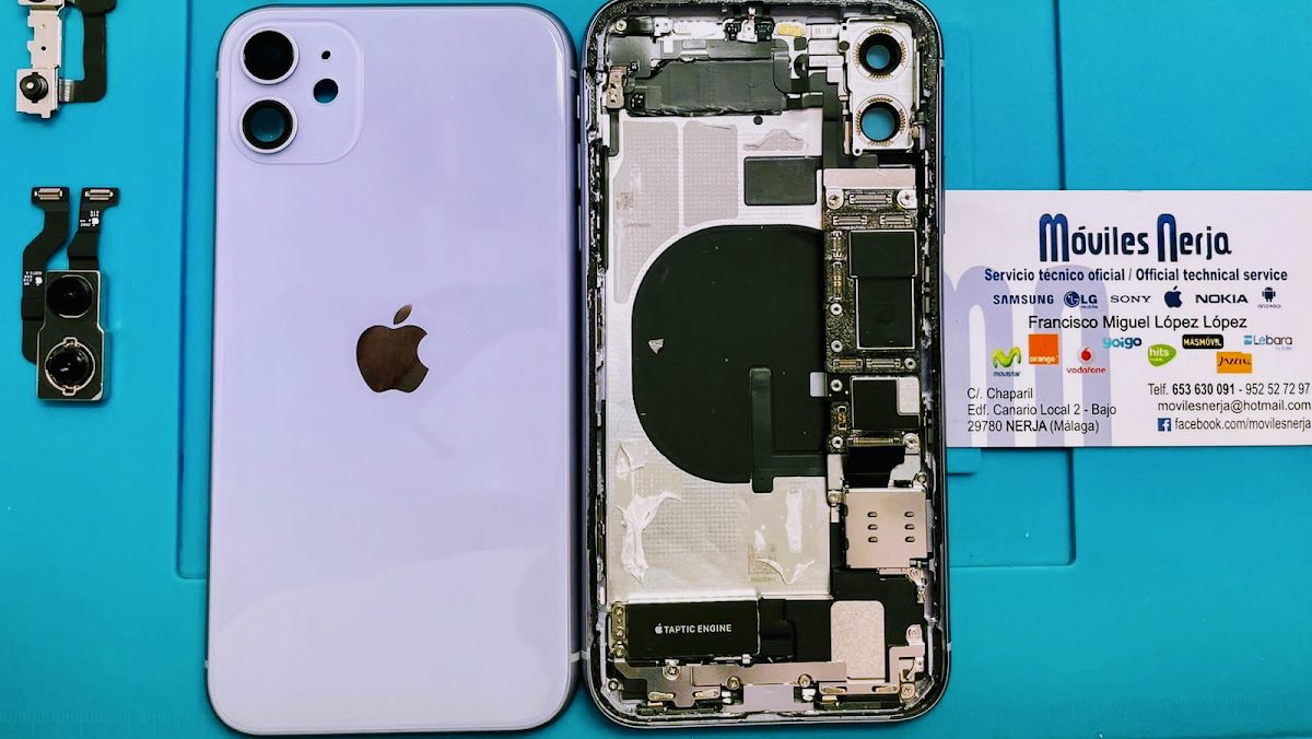 An opened iPhone 11 showing internal components, with a business card for MÒVILES NERJA beside it.