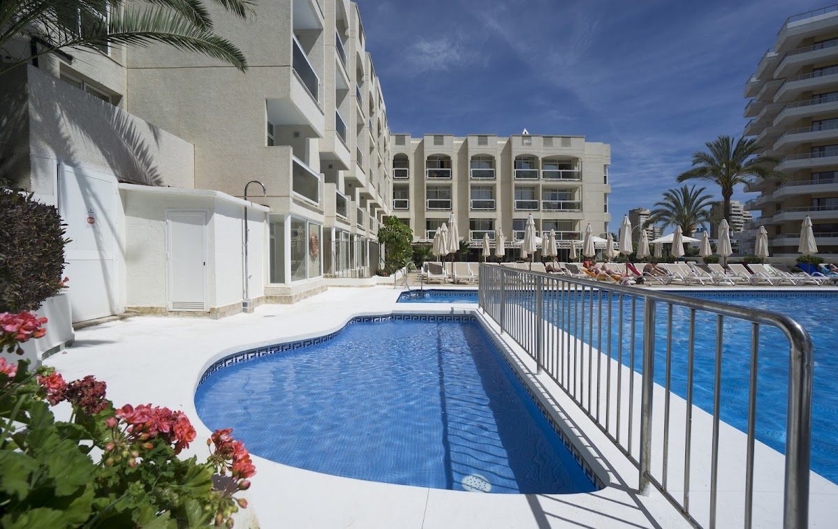 The image shows a pool area at MS Apartahotel Aguamarina, surrounded by sun loungers and palm trees.