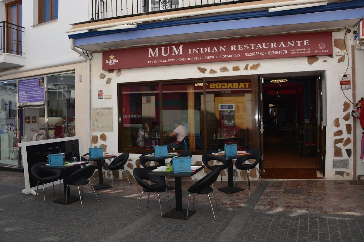 The exterior of Mum Nerja - Restaurante Indio features outdoor seating with tables and chairs in front of the restaurant.