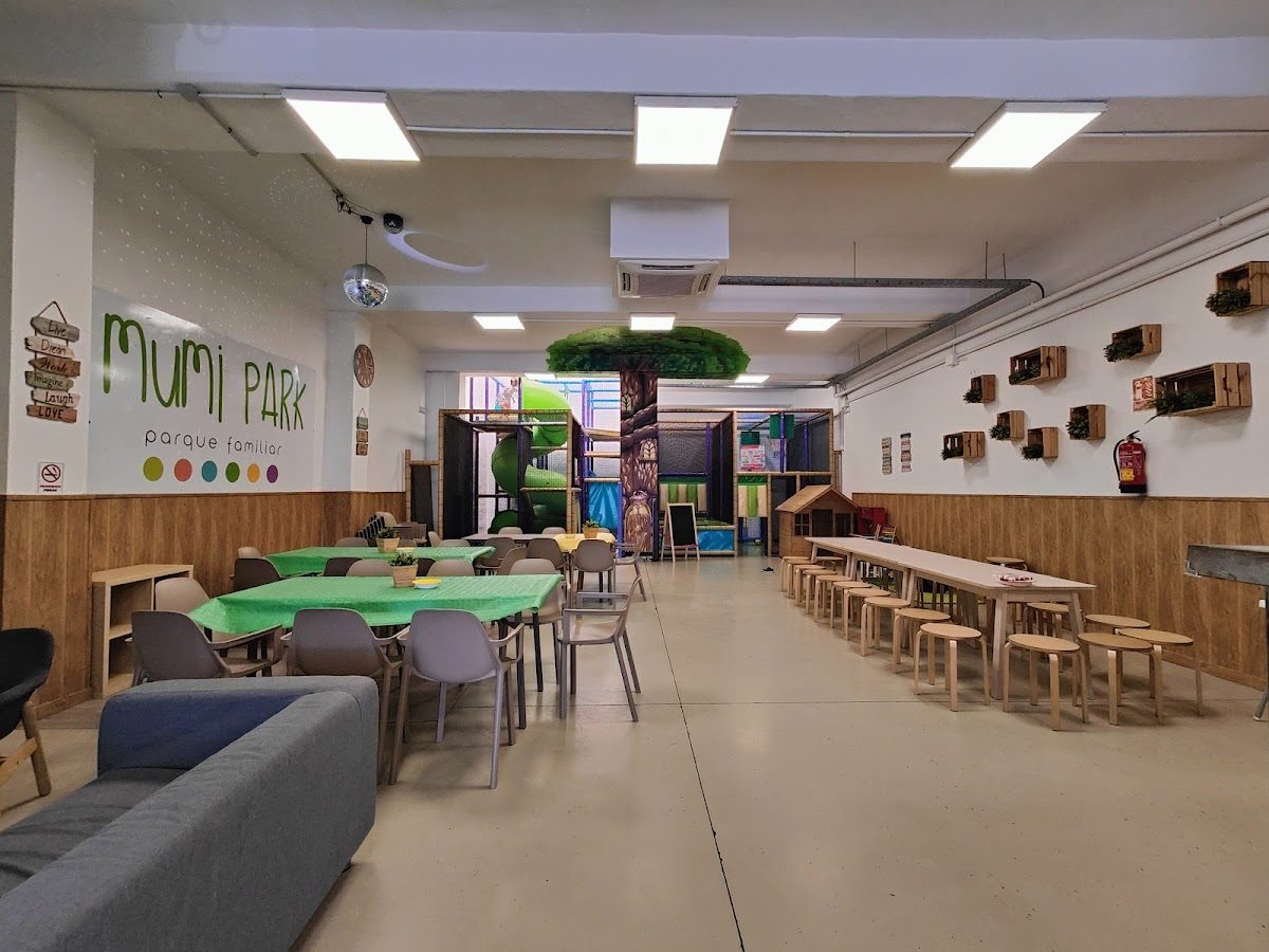 Interior del parque Mumi, con estructuras de juego, mesas y zonas de descanso para familias y niños.