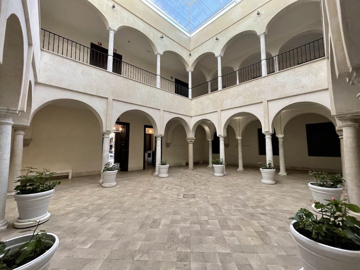 The interior courtyard of Museo Carmen Thyssen Málaga features columns, potted plants, and a glass ceiling.