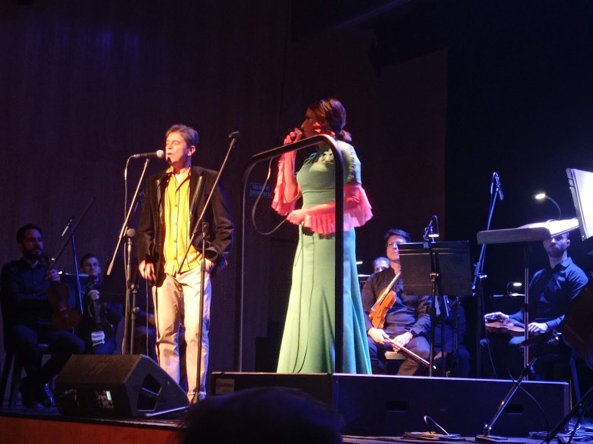 A performance at MVA Cultural Center featuring two singers on stage with musicians in the background.