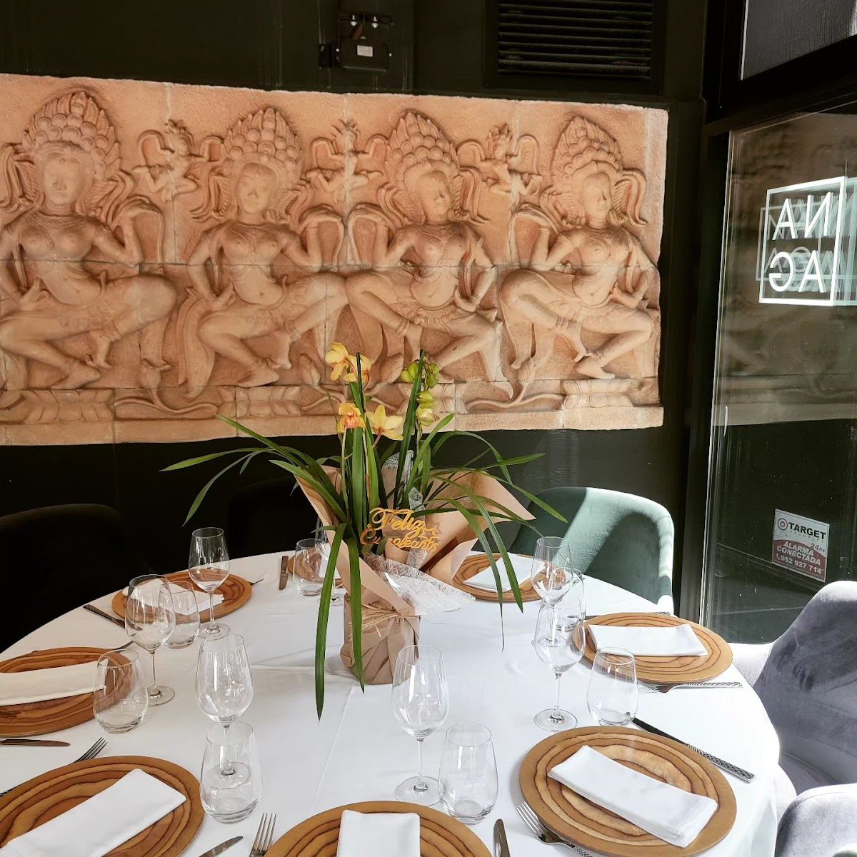 Elegante comedor en el restaurante tailandés Naga, con una pared decorativa y un centro de mesa floral.