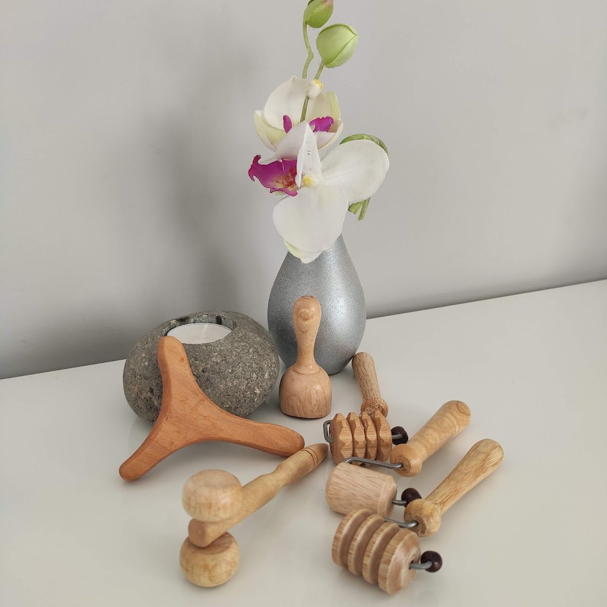 A selection of wooden massage tools and a decorative vase with flowers at Namaste Wellness Center.