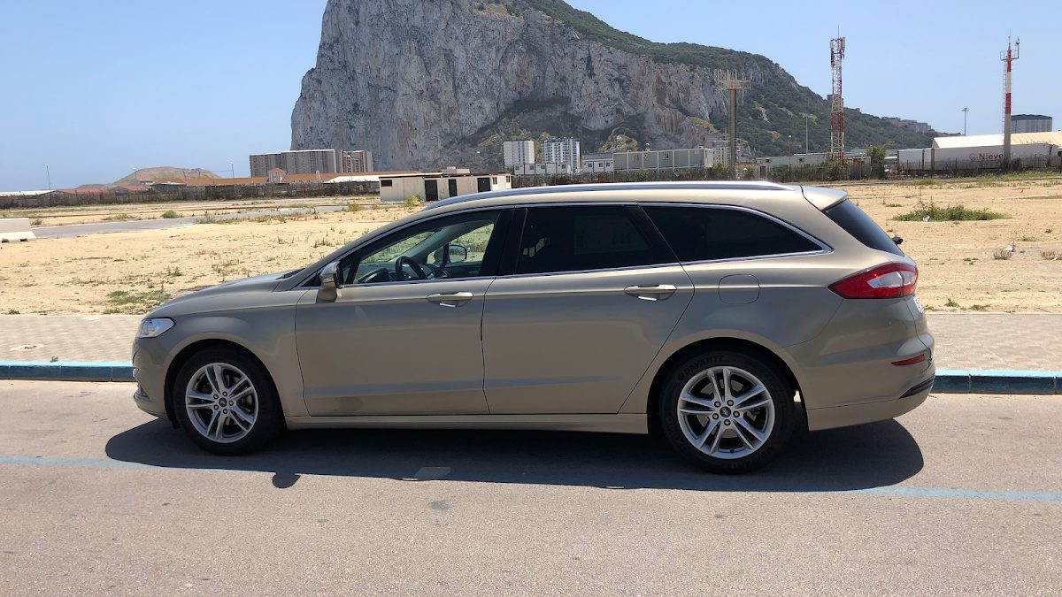 A silver station wagon parked beside a rocky hillside in Nerja, Málaga.