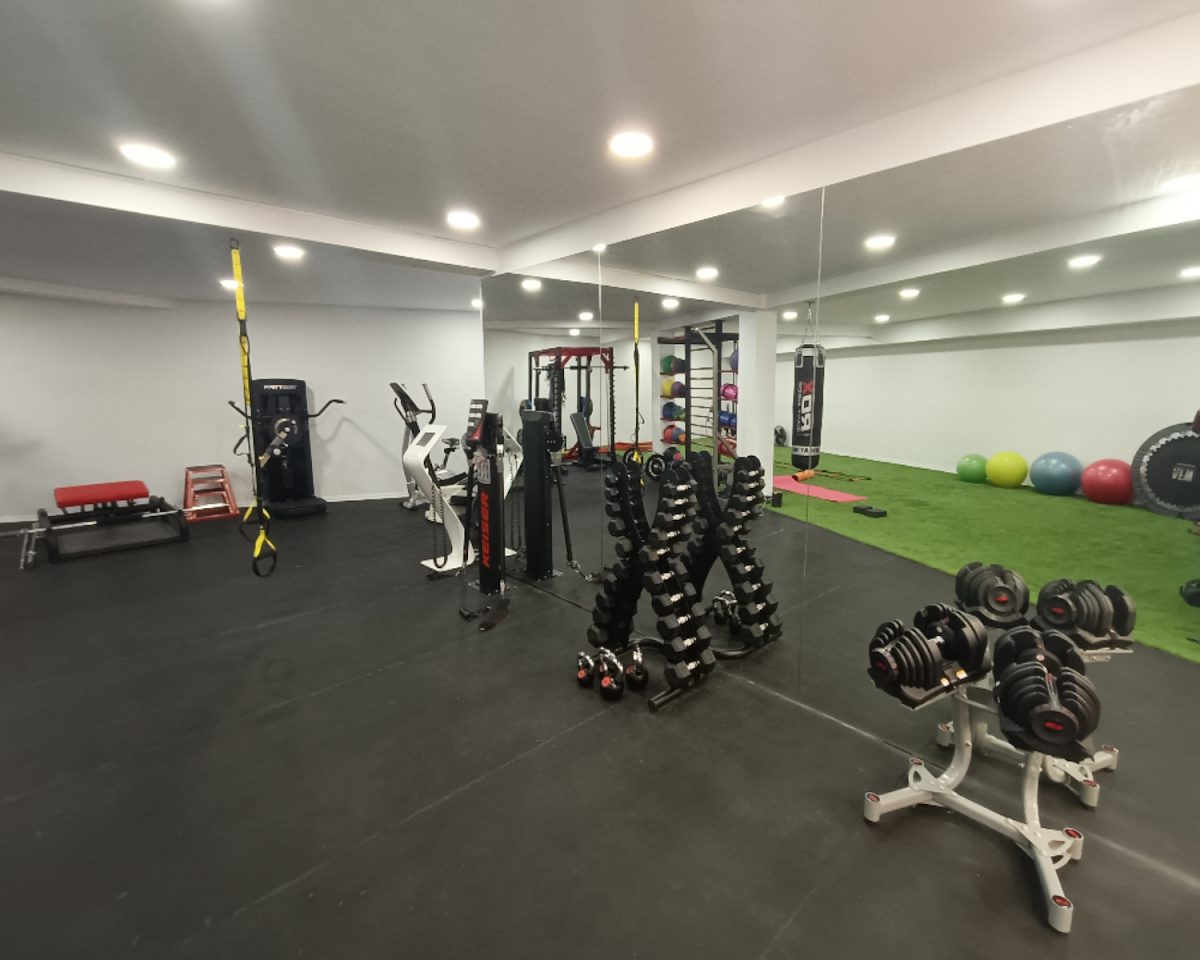 NEUS Physical Instructor ofrece un interior de gimnasio espacioso con pesas, máquinas de ejercicio y coloridas pelotas de fitness.