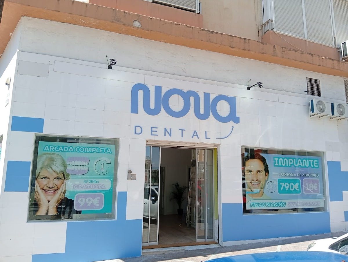El exterior de NOVADENTAL en Torremolinos presenta una fachada de color azul brillante y blanco con carteles promocionales.