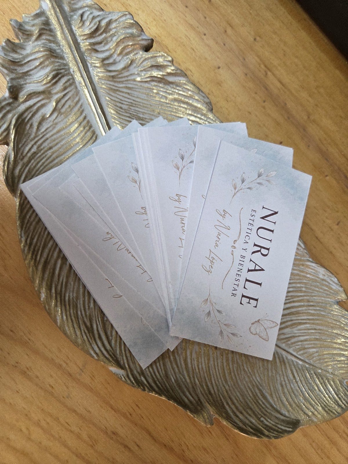 Business cards for Nurale Estética y Bienestar displayed on a decorative leaf-shaped tray.