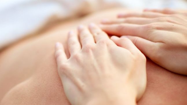 Primer plano de unas manos realizando un masaje en la espalda de una persona en Nuria Núñez Bienestar & Belleza.
